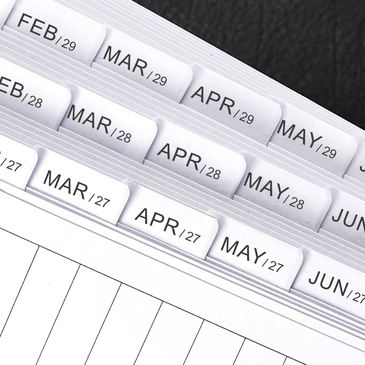 Close-up of tabbed A6 monthly planner refill pages labeled Feb/29 through Jun/28