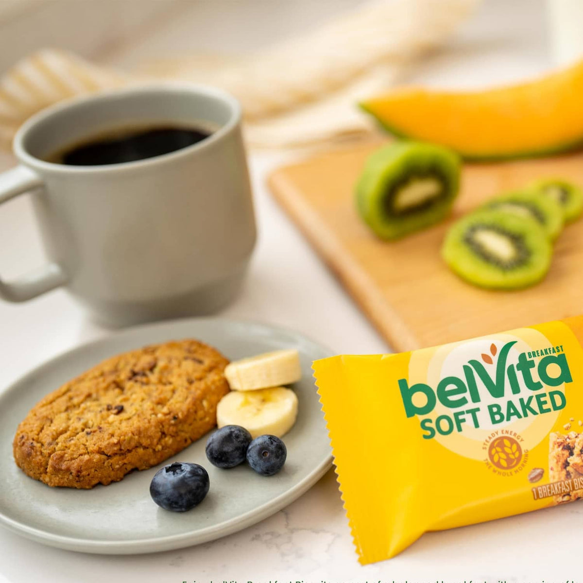 Soft baked banana bread biscuits on a plate with blueberries and banana, plus snack pack