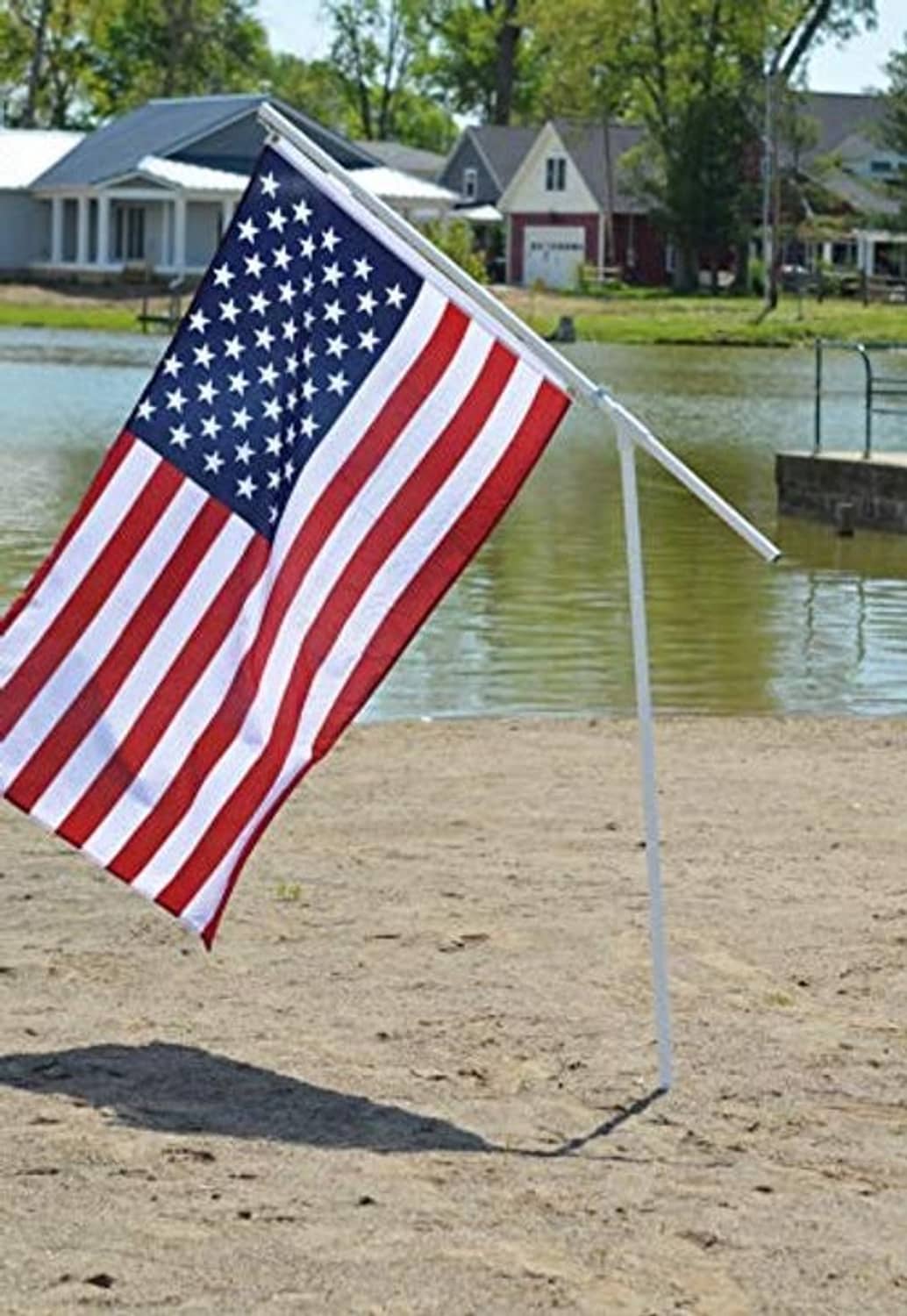 Portable flagpole with U.S. flag on tall pole and crossbar support
