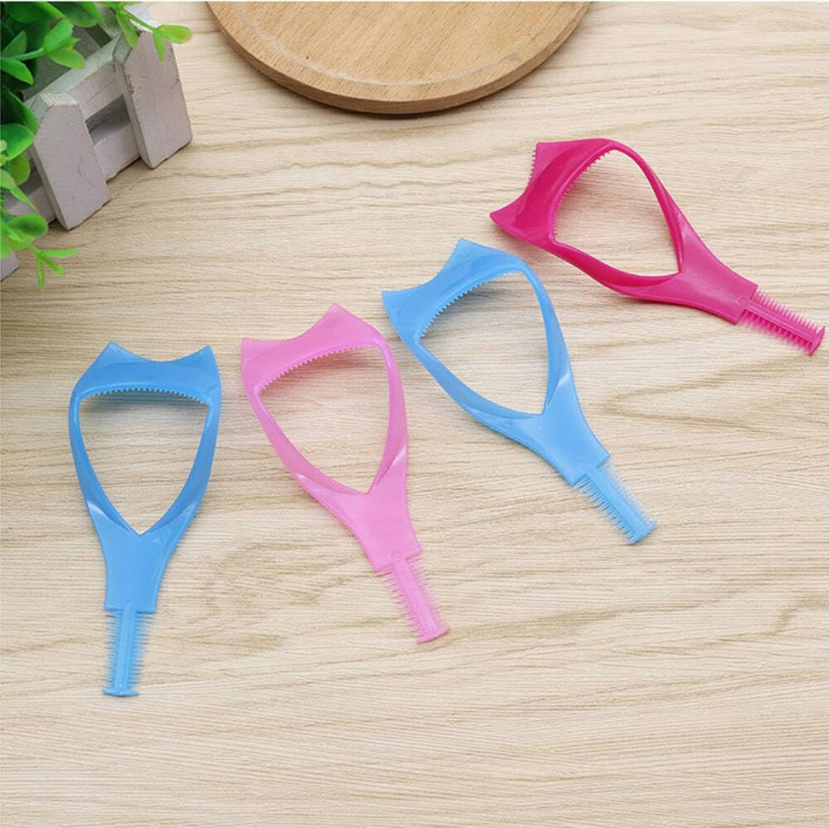 Assorted pink and blue eyelash shield tools laid out on a wooden board