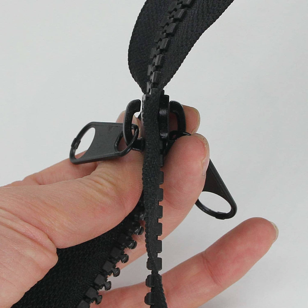 Close-up of black zipper slider with two metal pull rings and plastic track
