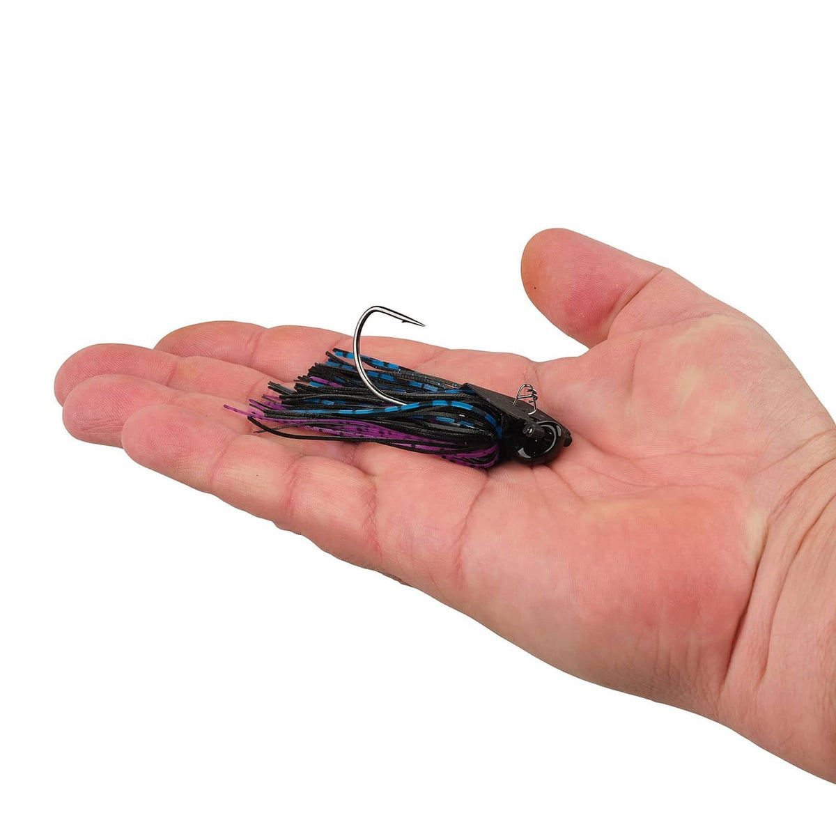 Fishing bladed jig held in hand, black blade with blue and purple skirt