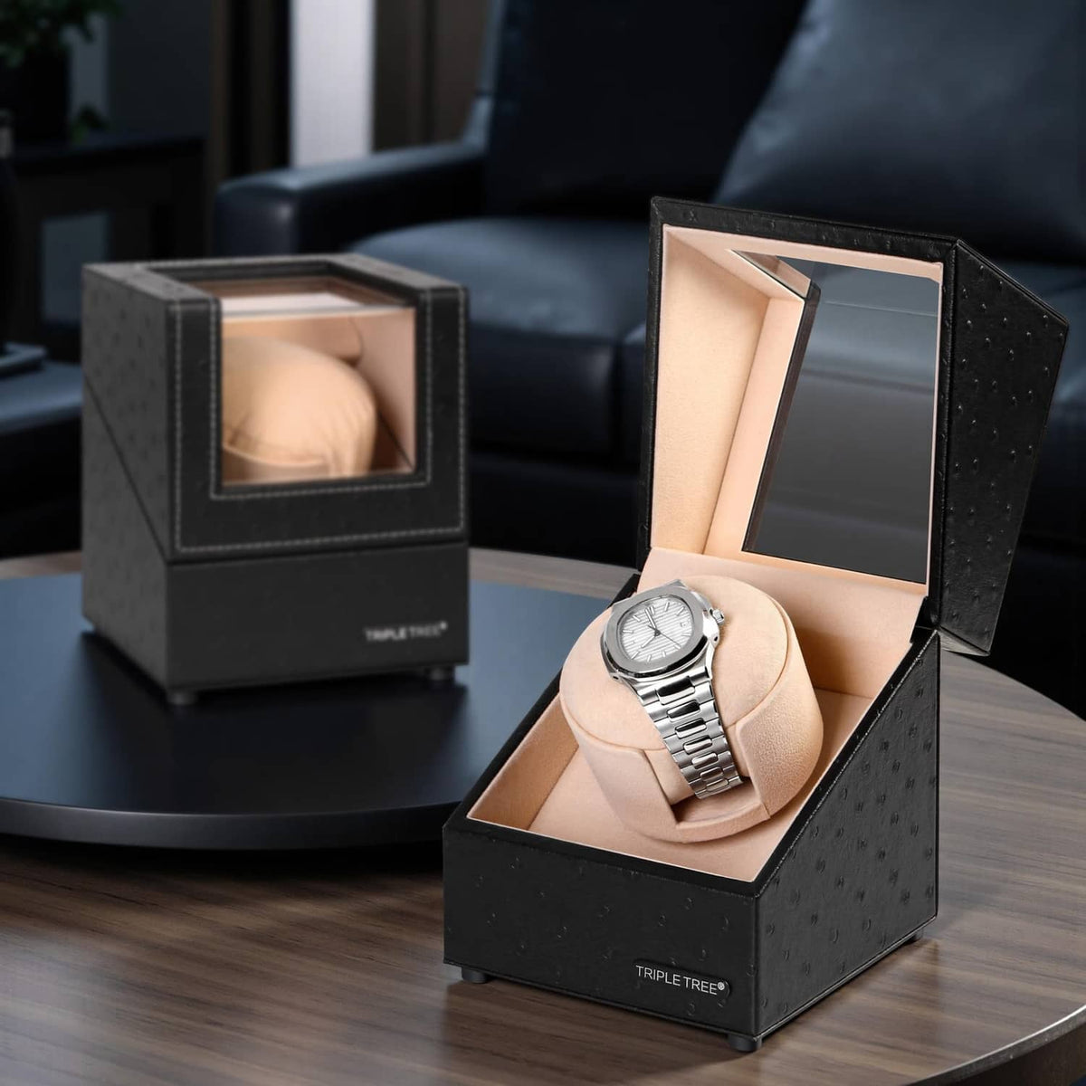 Two black watch winders with beige pillows; one open with a wristwatch visible