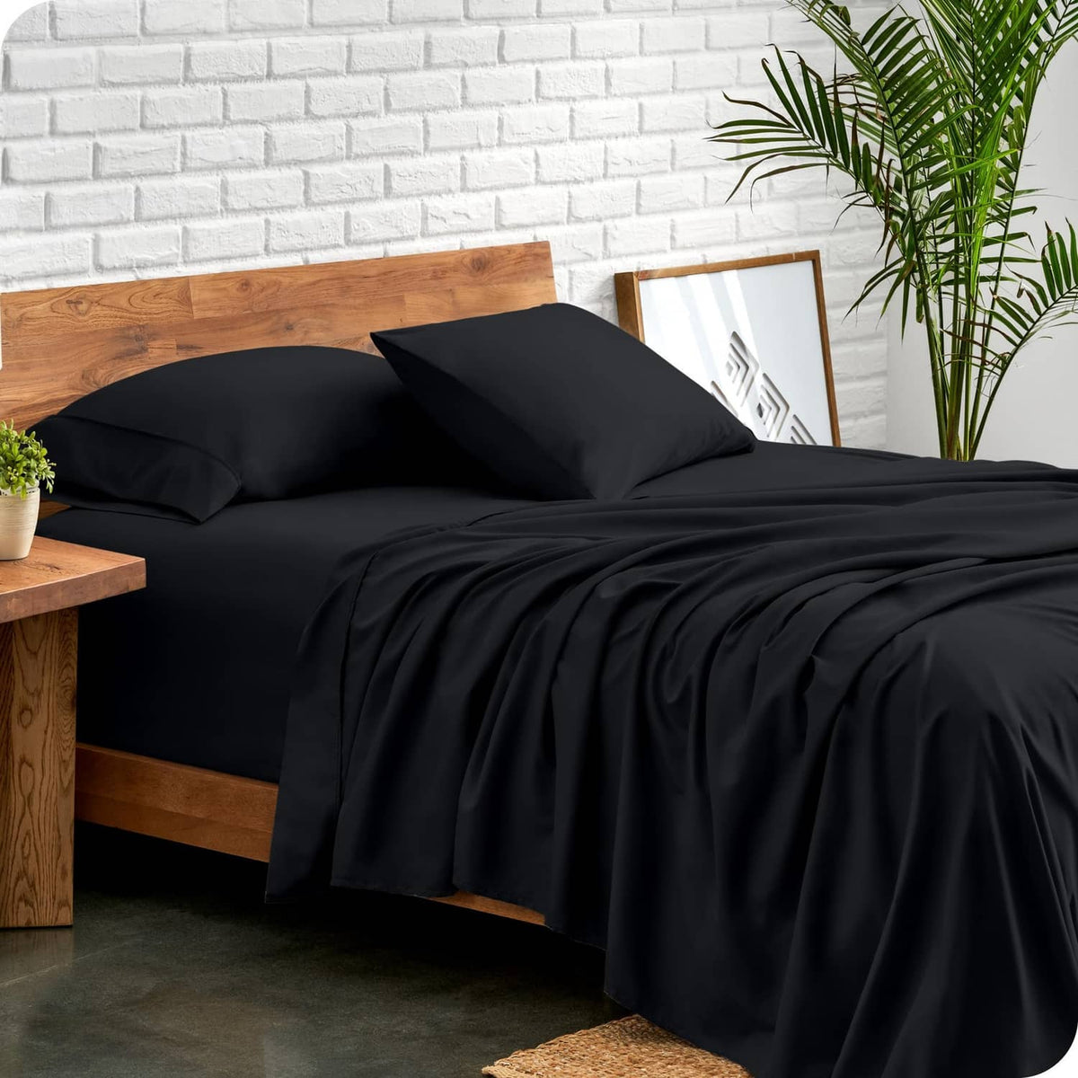 Black king bedding set with two pillow shams and draped comforter on a bed