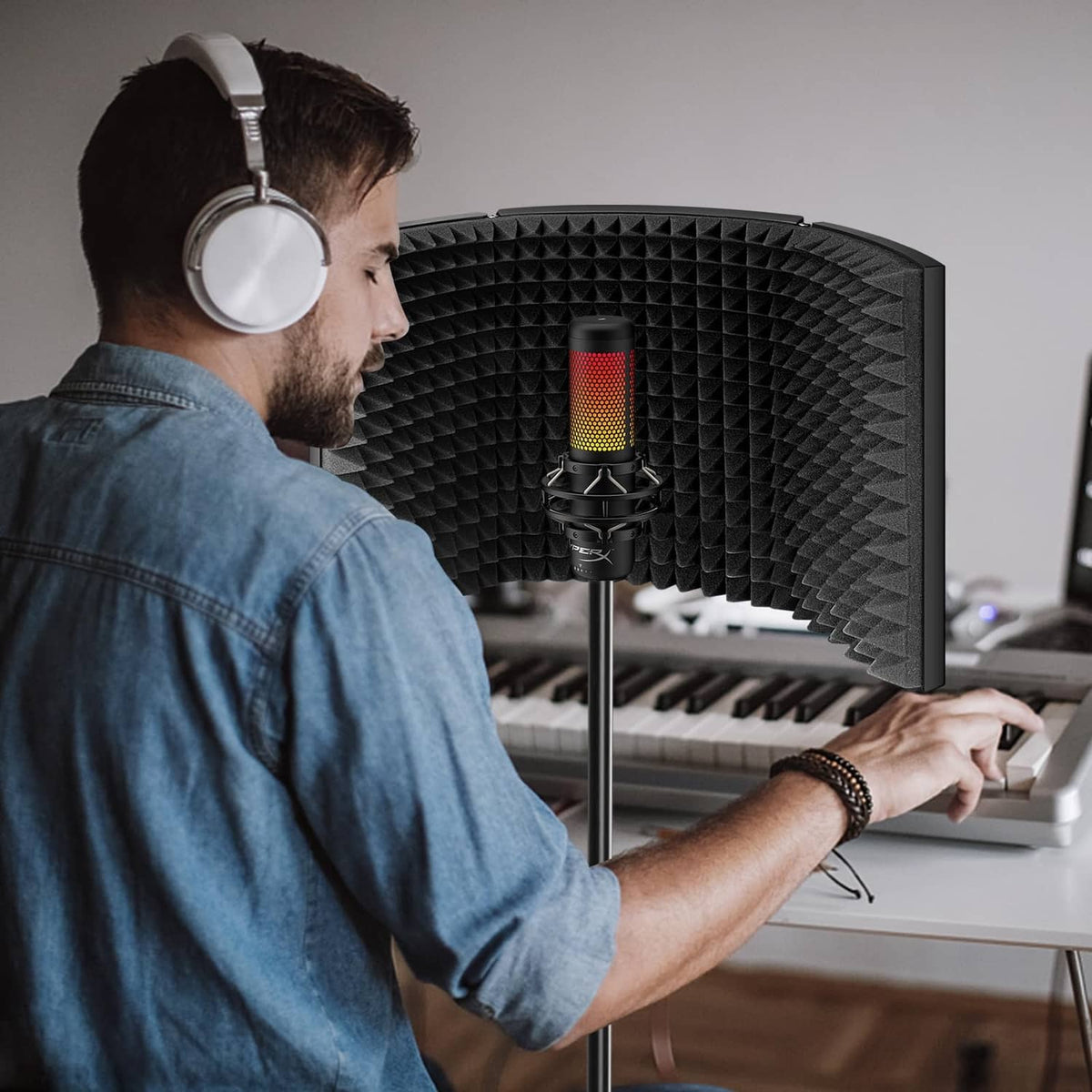 Curved microphone isolation shield with black acoustic foam panels around a condenser mic