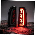 Pair of black LED tail light housings with bright red sequential arrow pattern lit