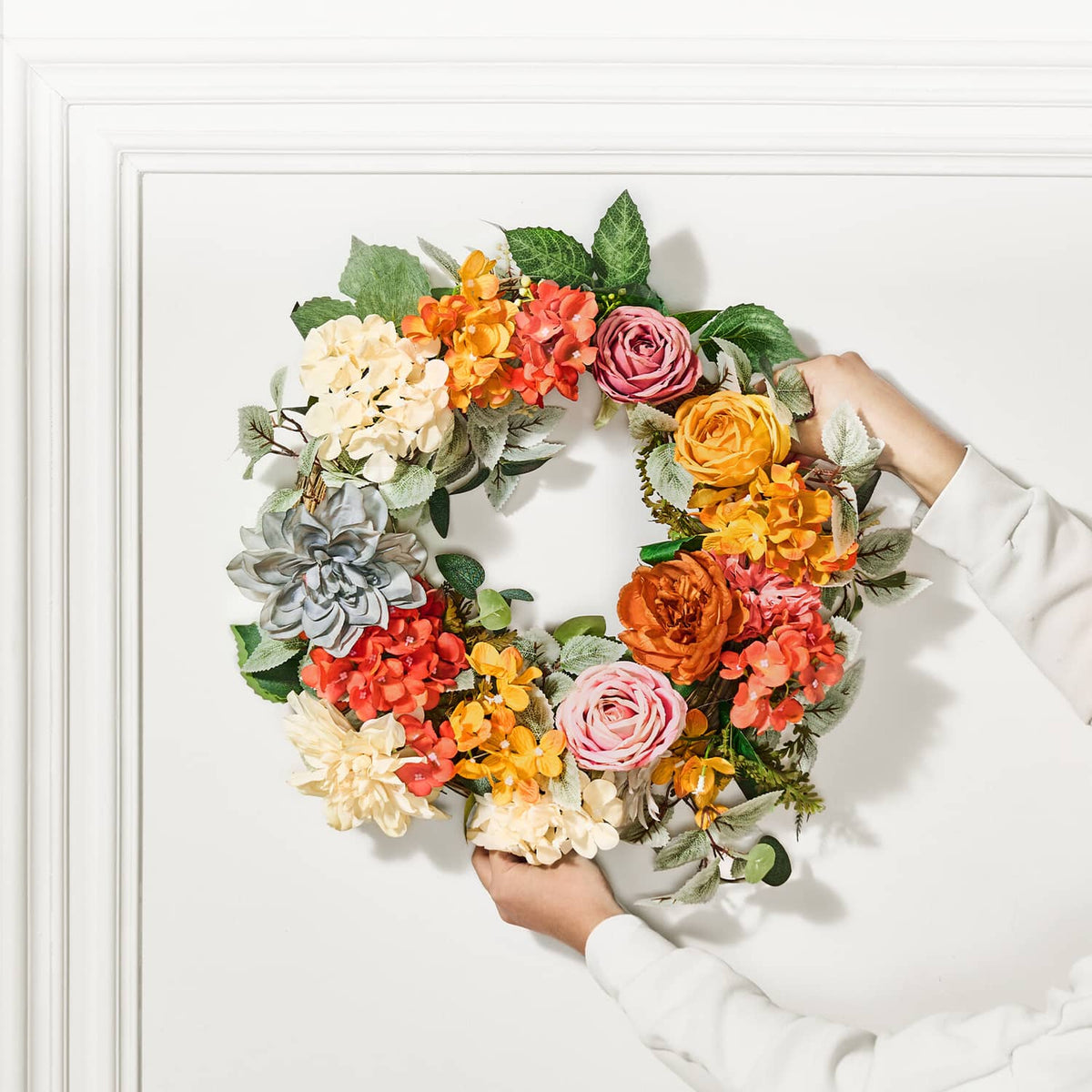 Floral wreath with welcome sign, orange red yellow roses and hydrangeas, close-up