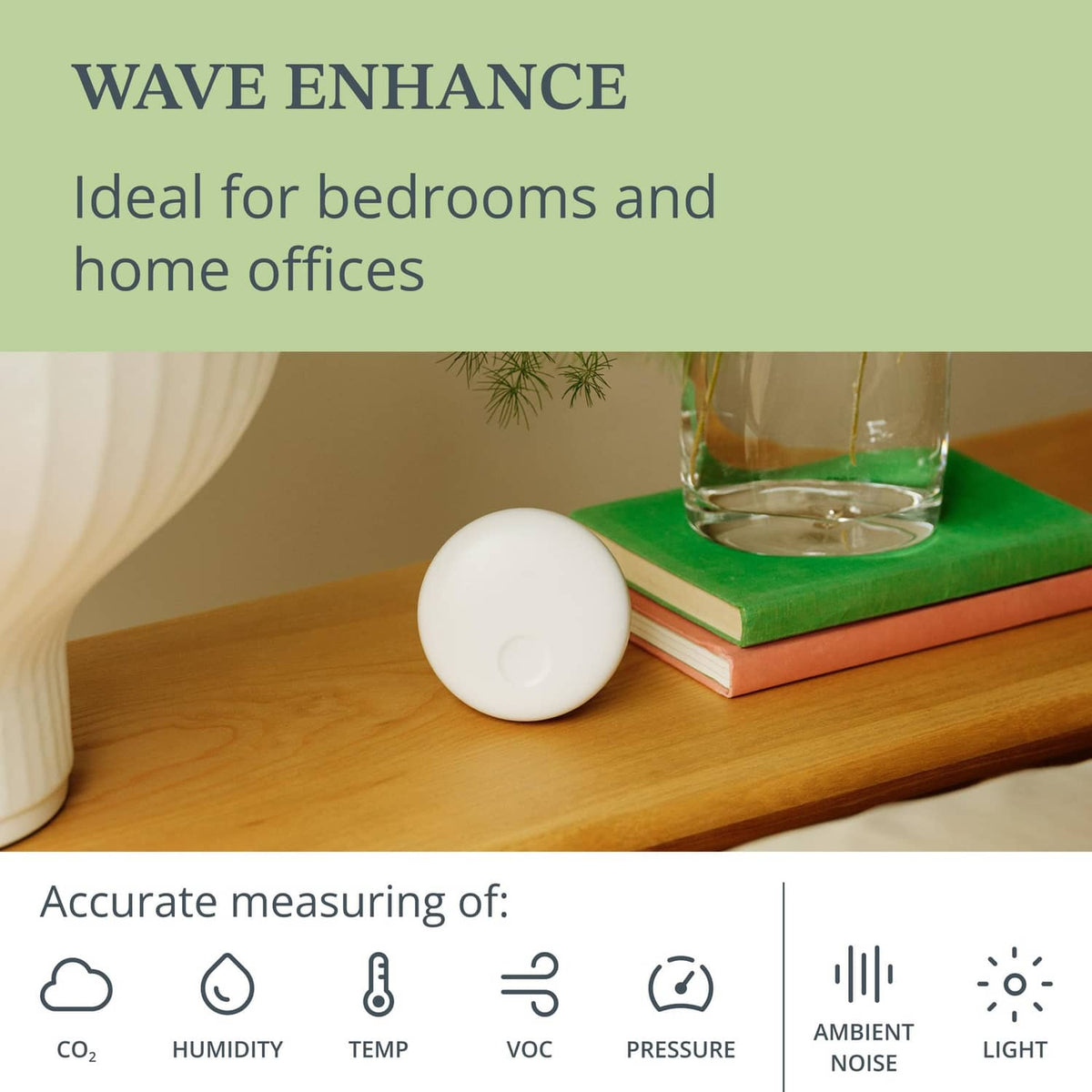 White indoor air quality monitor on books with green status light on desk