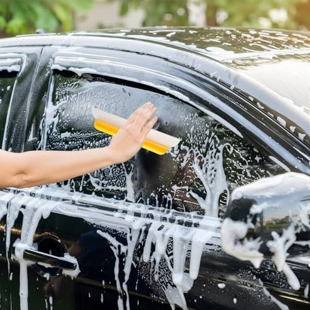 Car drying squeegee with black silicone blade pulling water from the windshield