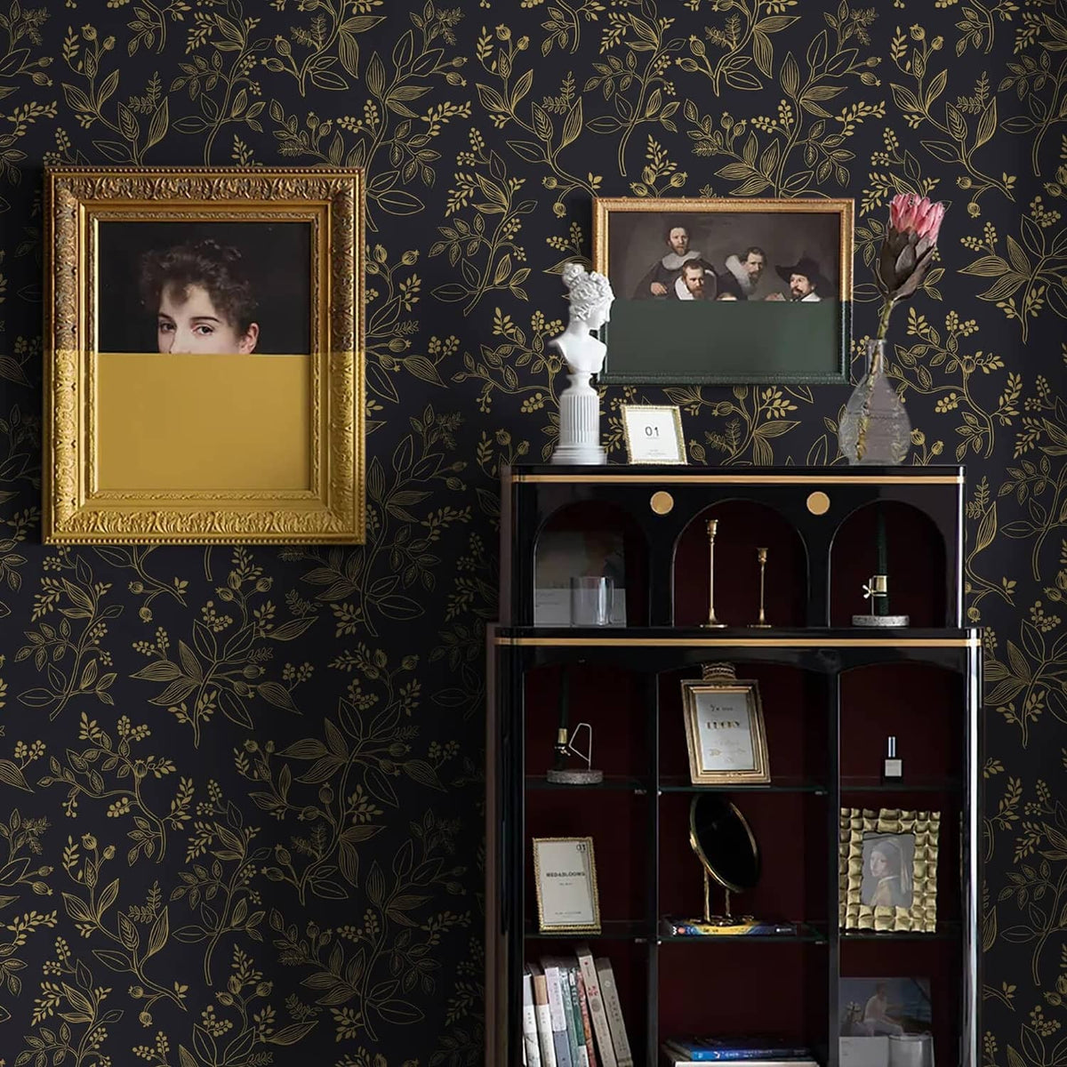 Black and gold botanical wallpaper backdrop behind glass display cabinet and frames