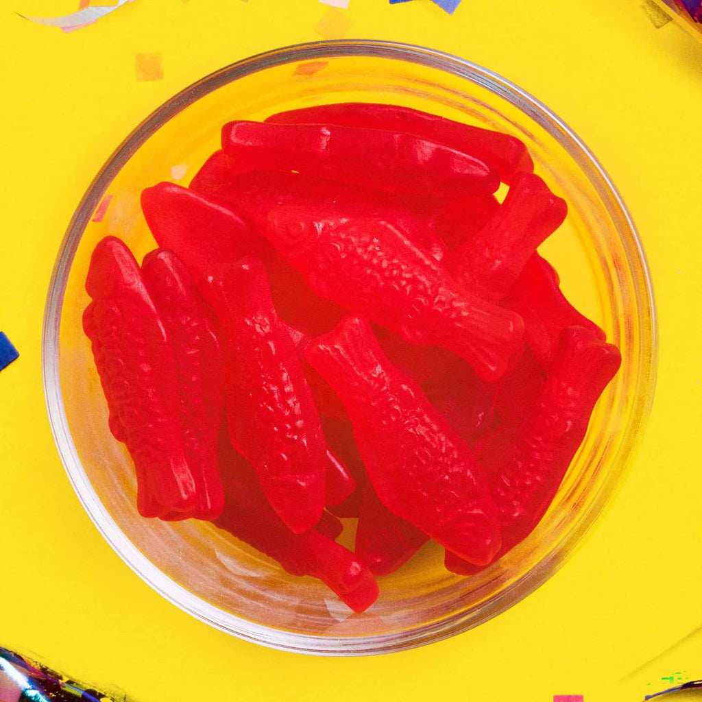 Red gummy fish candies in a clear glass bowl