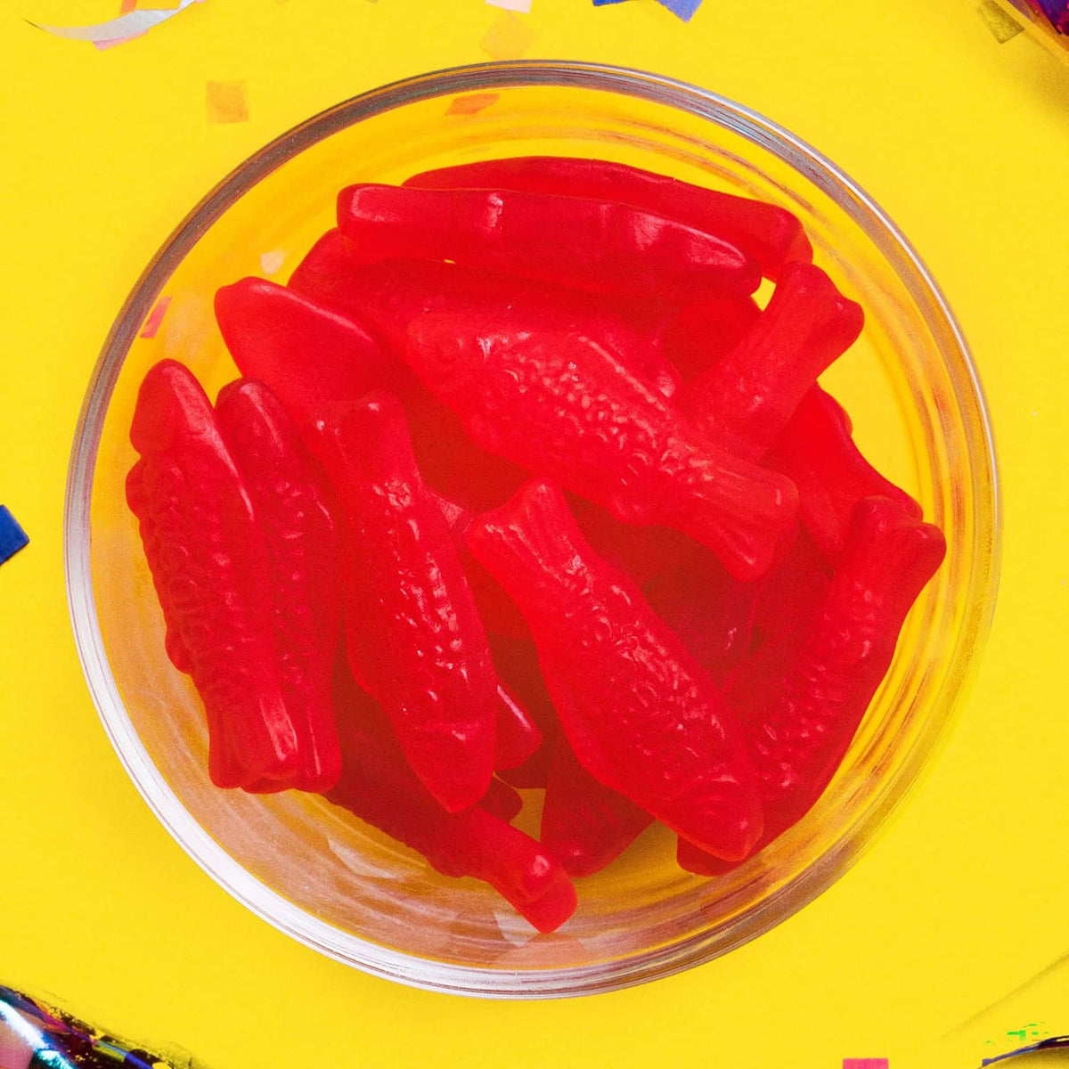 Red gummy fish candies in a clear glass bowl