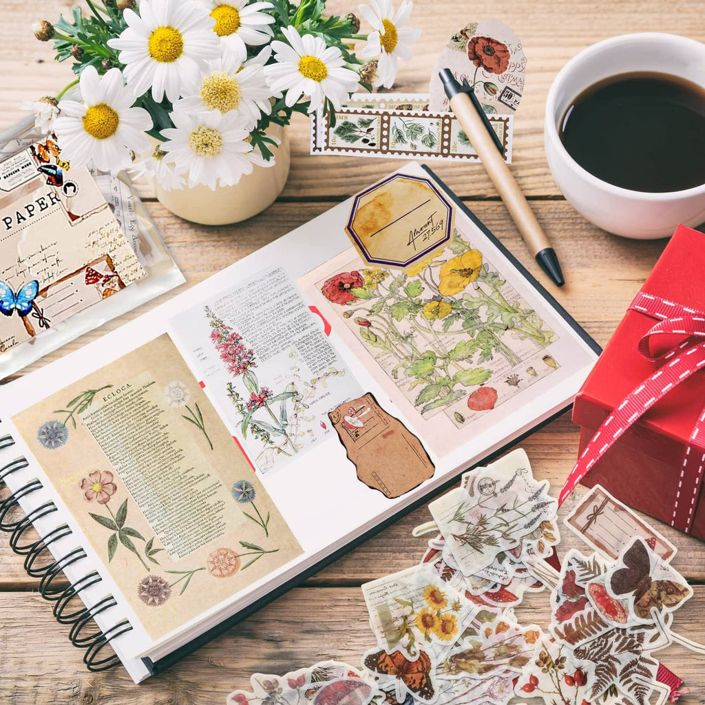 Junk journal craft stickers and printed papers on tabletop with flowers and butterfly accents