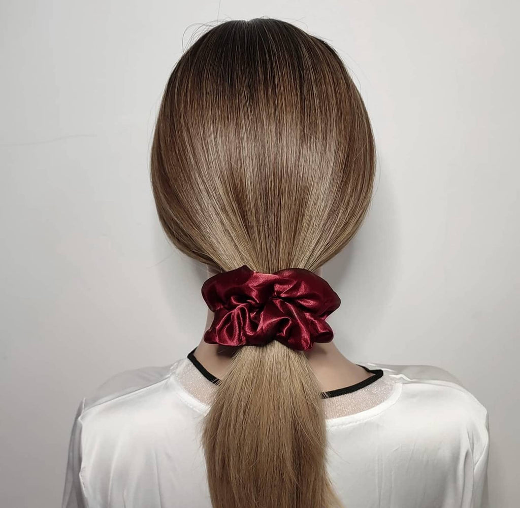 Wine red satin hair scrunchie holding a ponytail at the back of the head