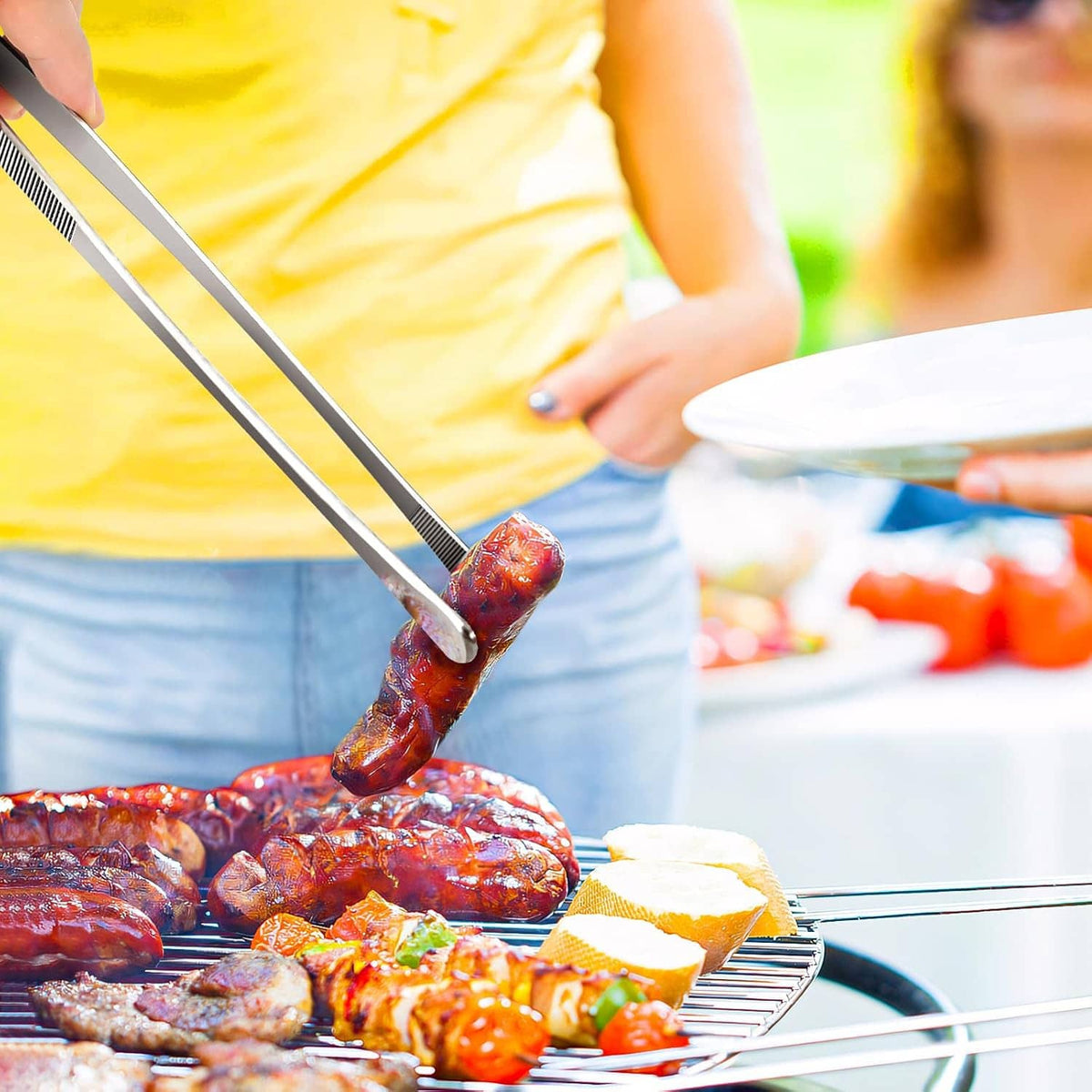 Stainless steel kitchen tweezers with ribbed grip, lifting seasoned meat from a grill