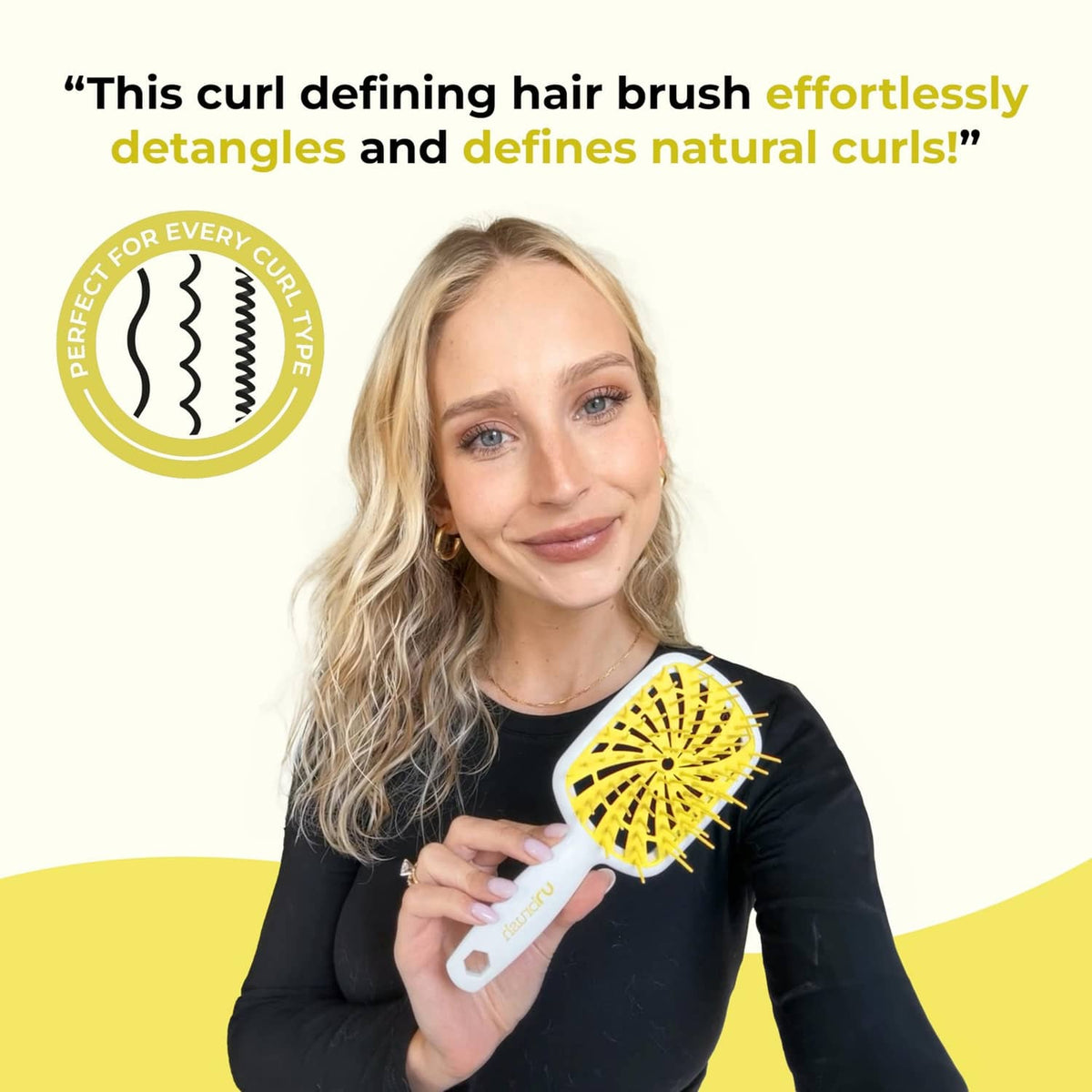 Detangling hair brush held in hand with yellow bristle head and white handle