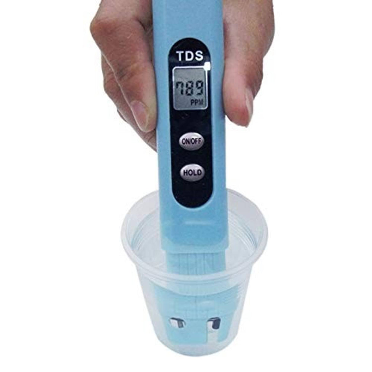 Digital TDS salinity tester held in hand above sampling cup, LCD reading visible