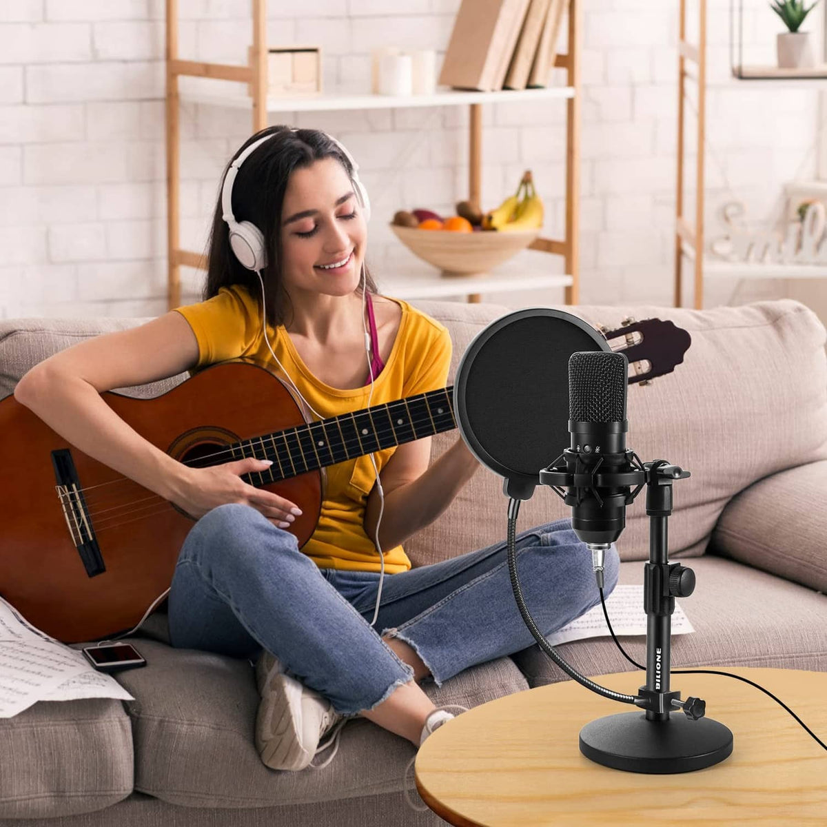 Black desktop microphone with round pop filter on stand used for recording vocals