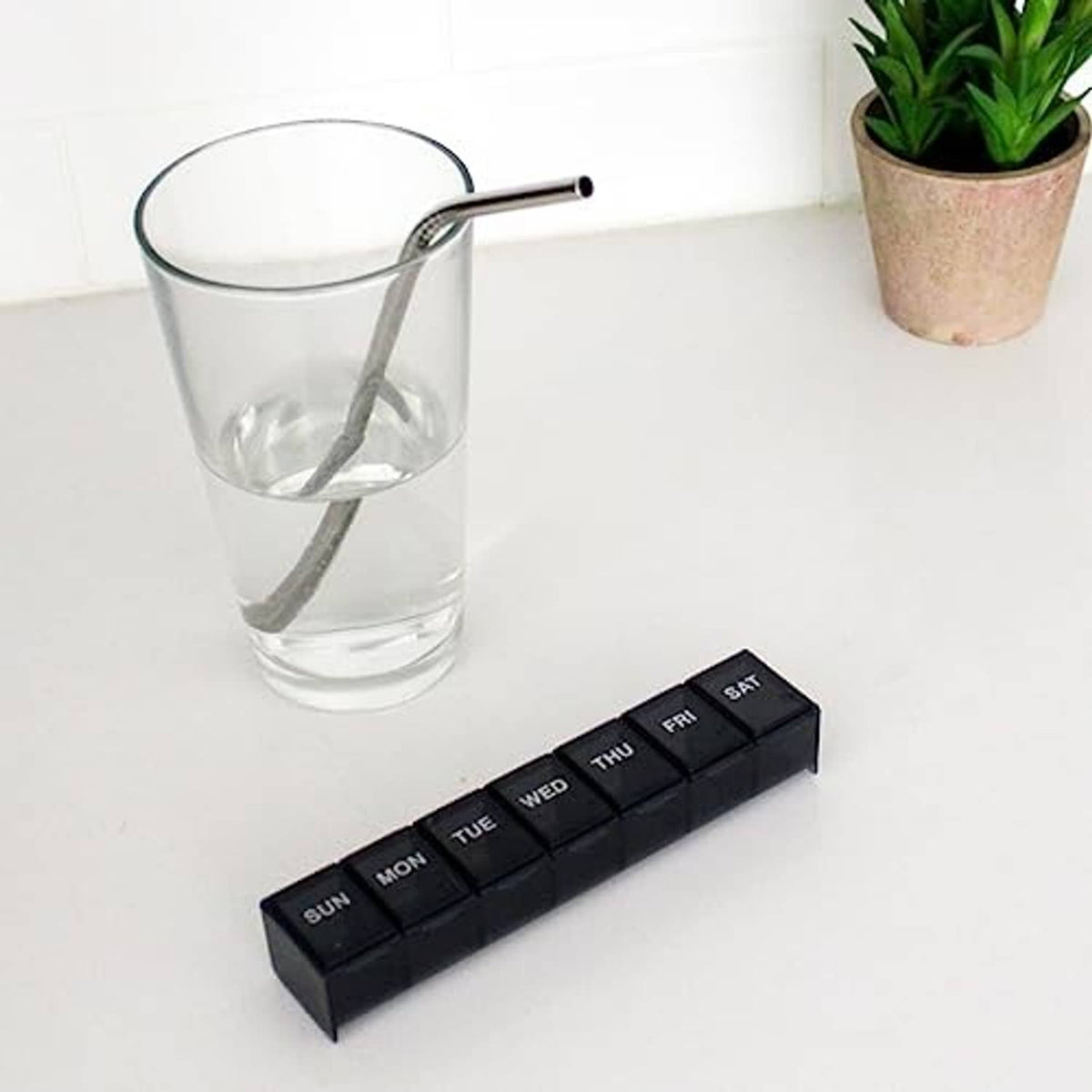 7-day pill case organizer with labeled days Mon–Sun, dark gray/black