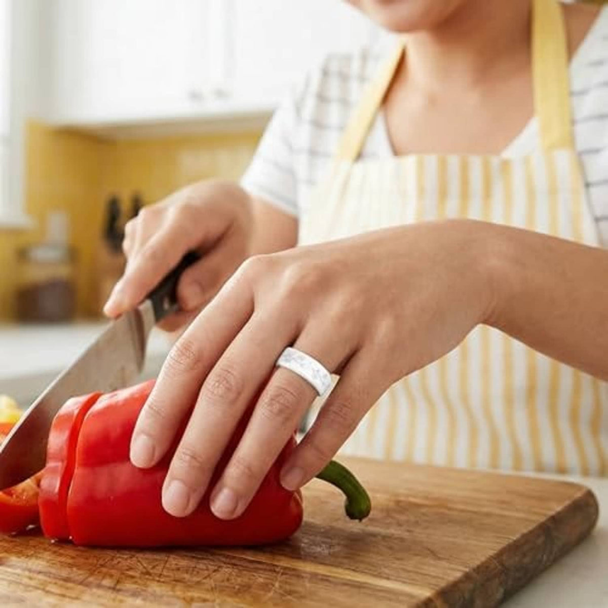 Silicone daisy ring cover on finger while chopping vegetables on a cutting board