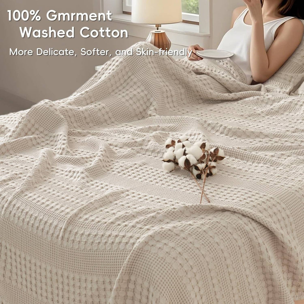 Ivory waffle-weave cotton blanket draped over a bed, showing raised grid texture