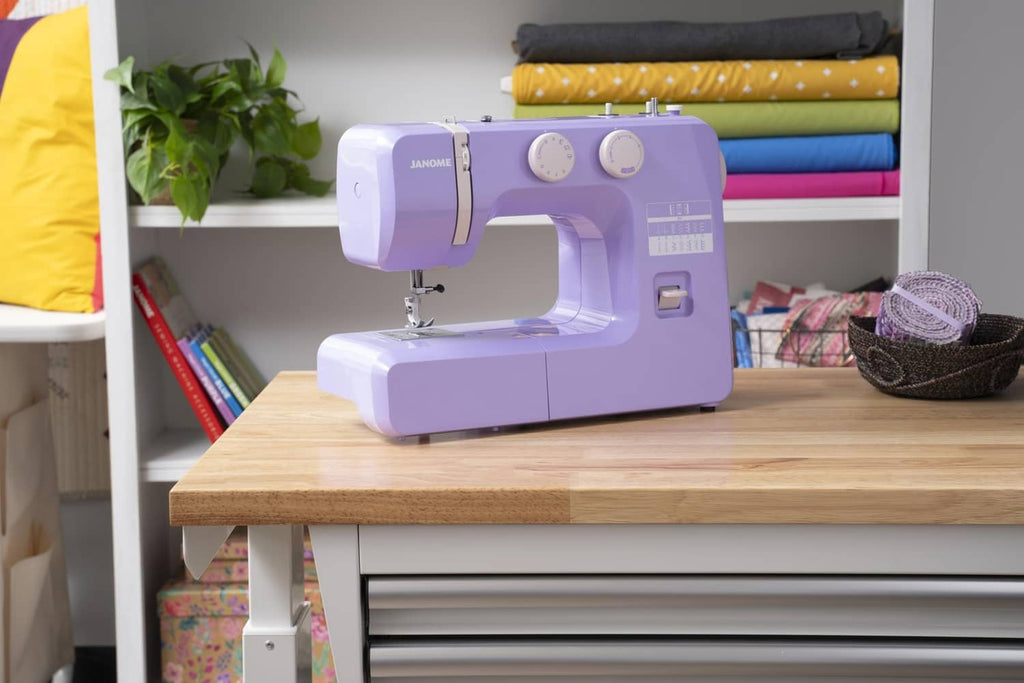 Purple Janome sewing machine on a worktable with dials and stitch panel visible