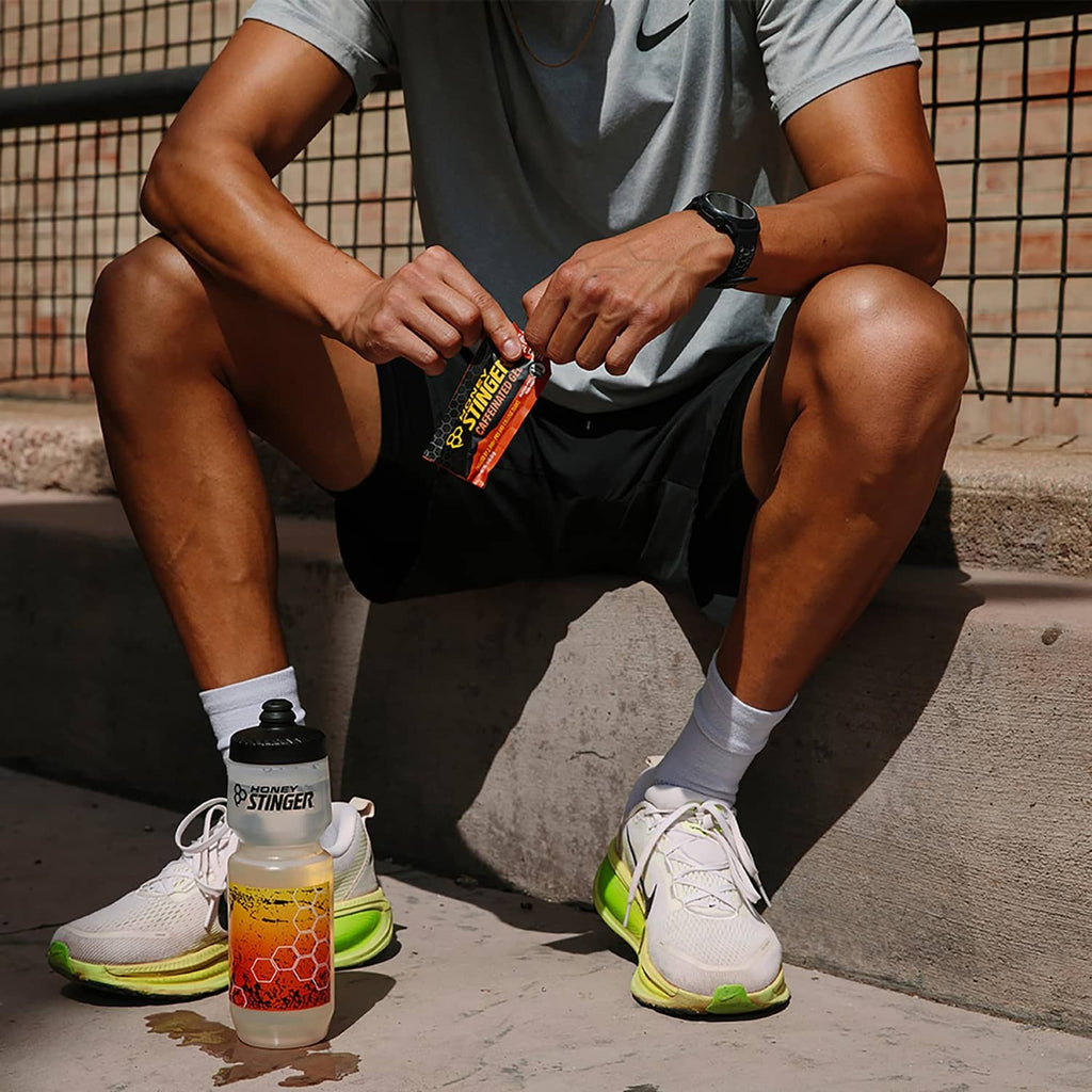 Caffeinated organic energy gel packet held by runner, Honey Stinger branded