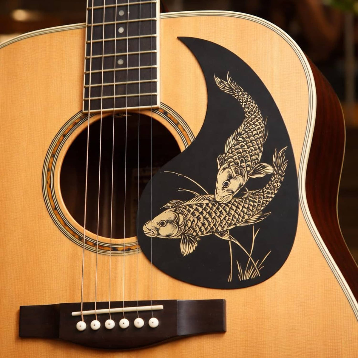 Guitar pickguard sticker on acoustic guitar body, black teardrop with gold fish