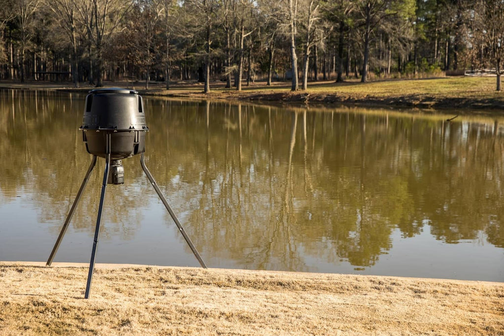 Directional feeder kit on tripod legs by water, matte black hopper housing