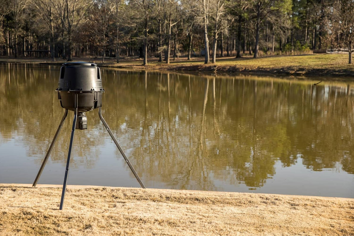 Directional feeder kit on tripod legs by water, matte black hopper housing