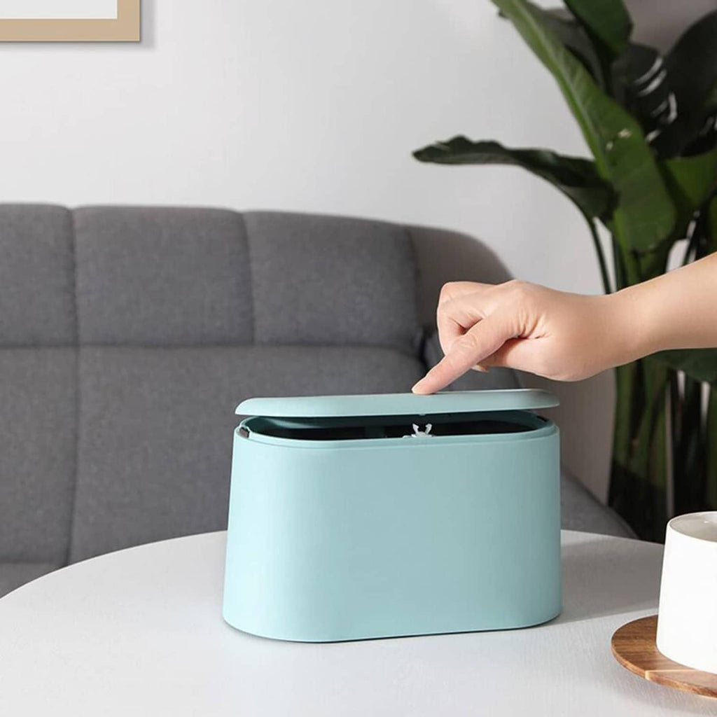 Light blue mini trash can with lid open on a round white table