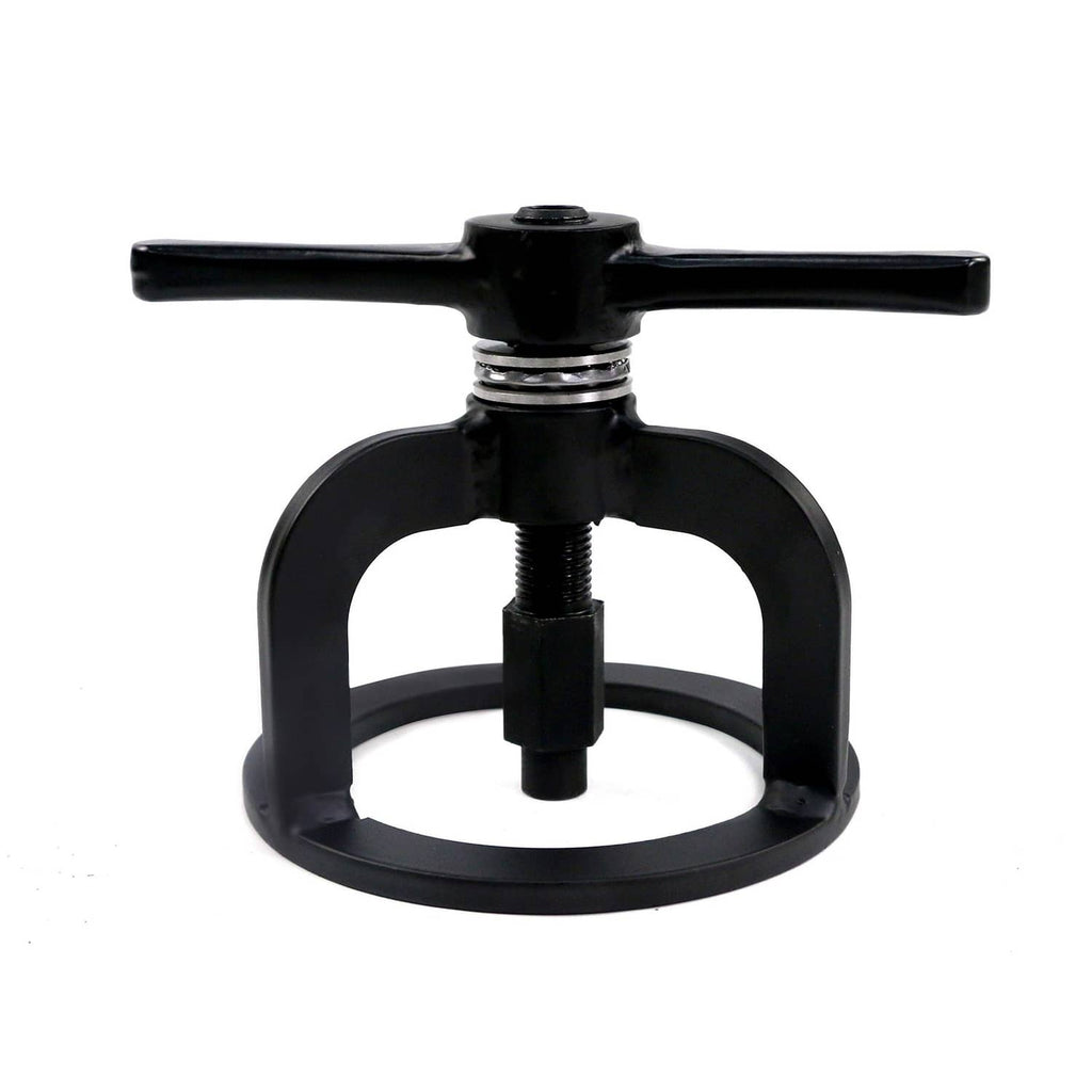 Black spring compressor tool with top handle, central threaded screw, and circular frame