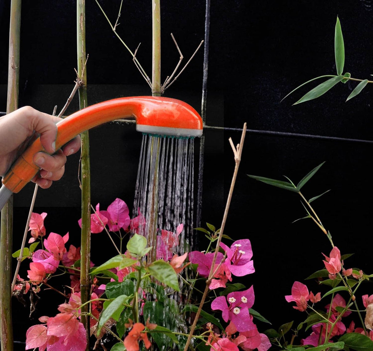 Handheld portable shower spraying water through orange top sprayer