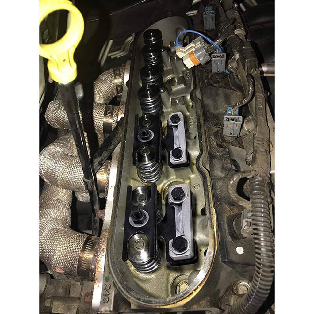 Valve spring compressor tool in engine bay with threaded studs and black bracket