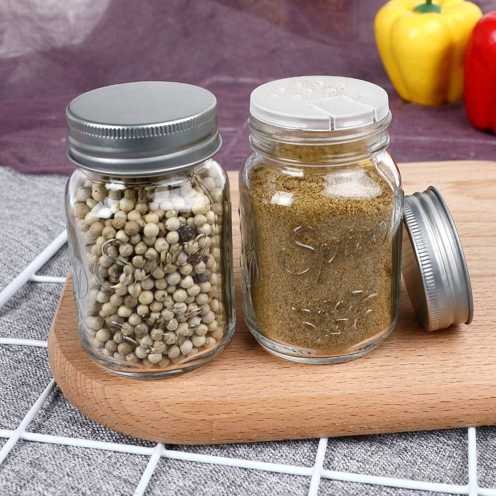 Two clear glass mason spice jars with silver lids on a wooden tray