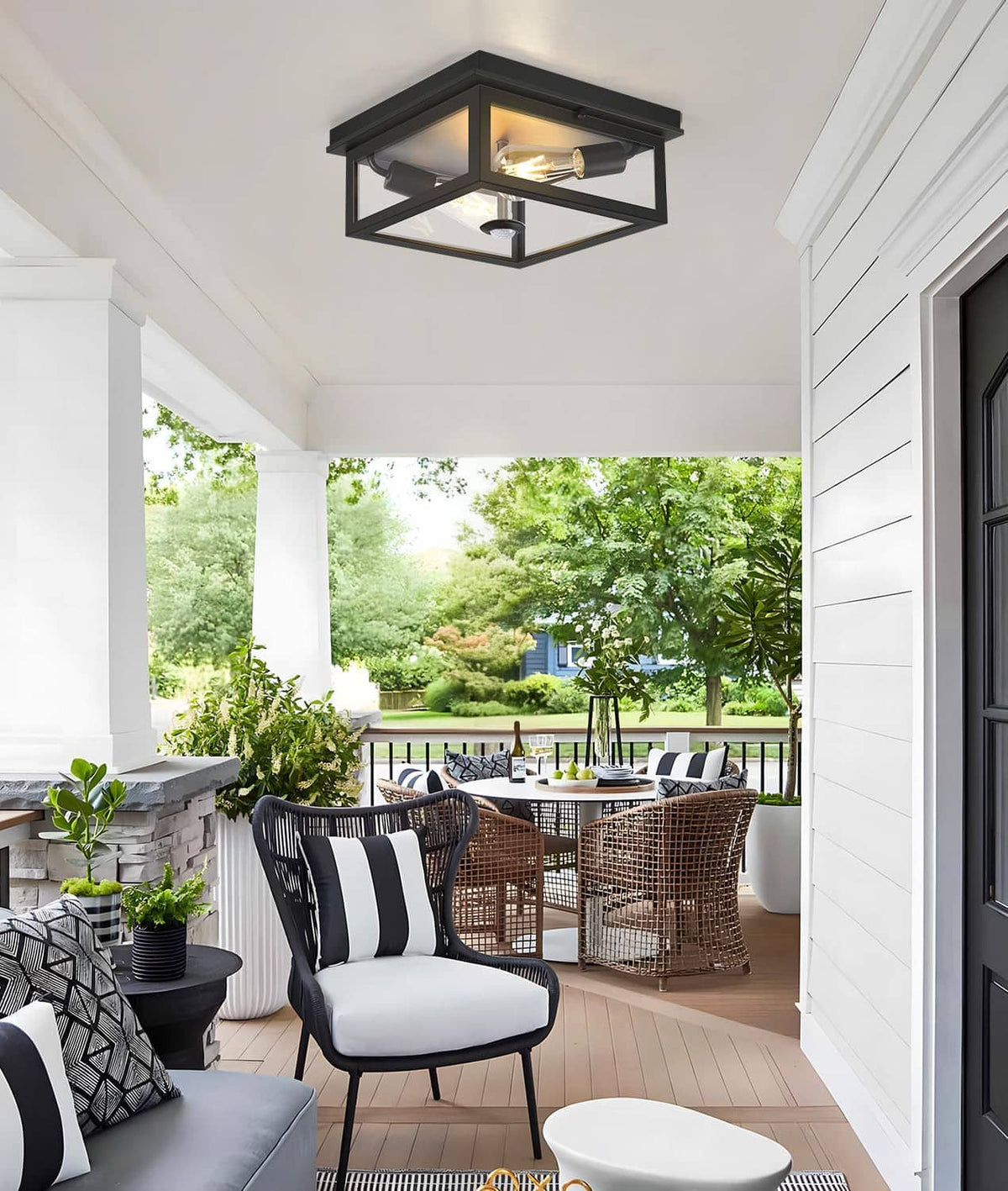 Black flush-mount outdoor ceiling light with motion sensor and illuminated exposed bulb.