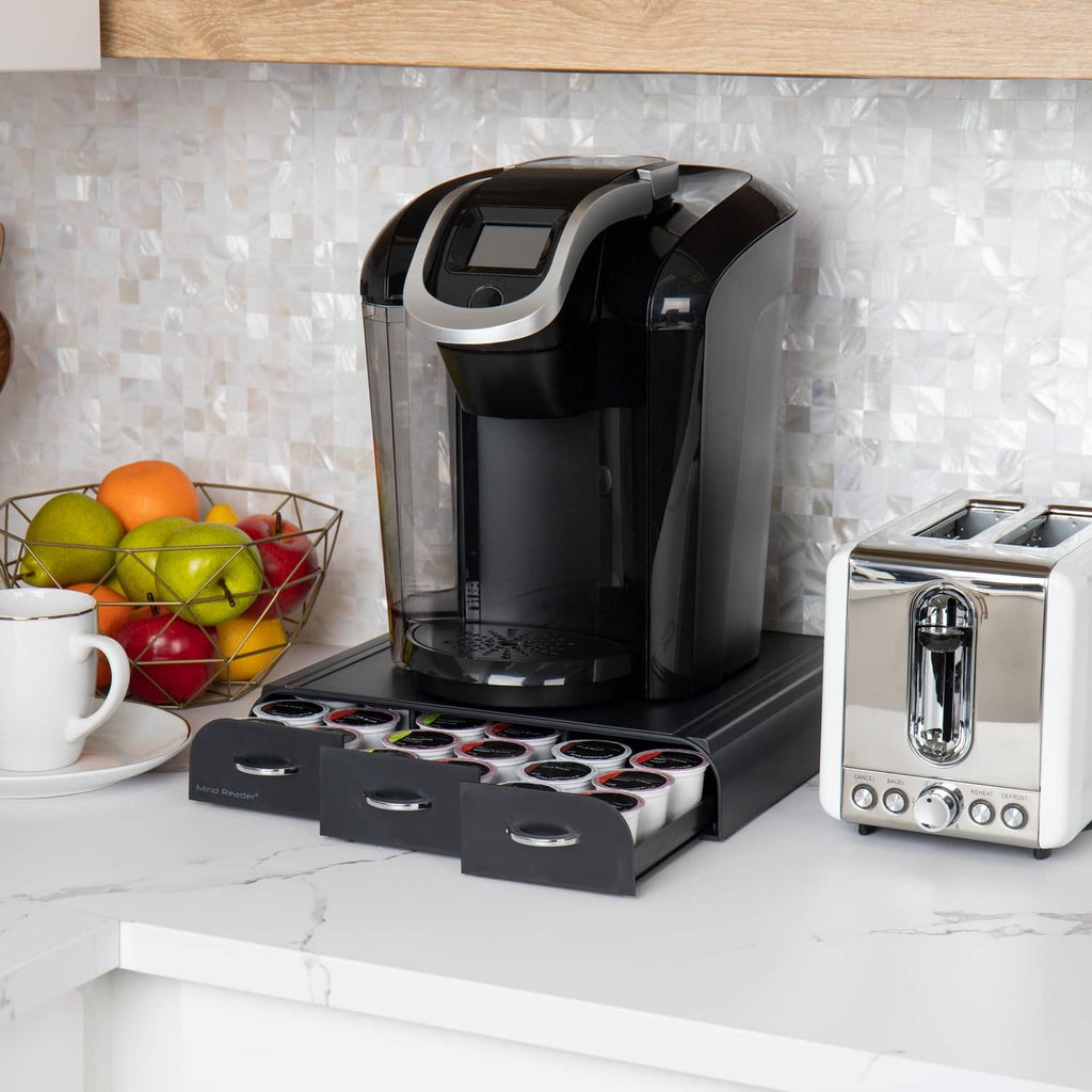 Black 3-drawer coffee pod organizer with open compartments holding assorted pod sleeves