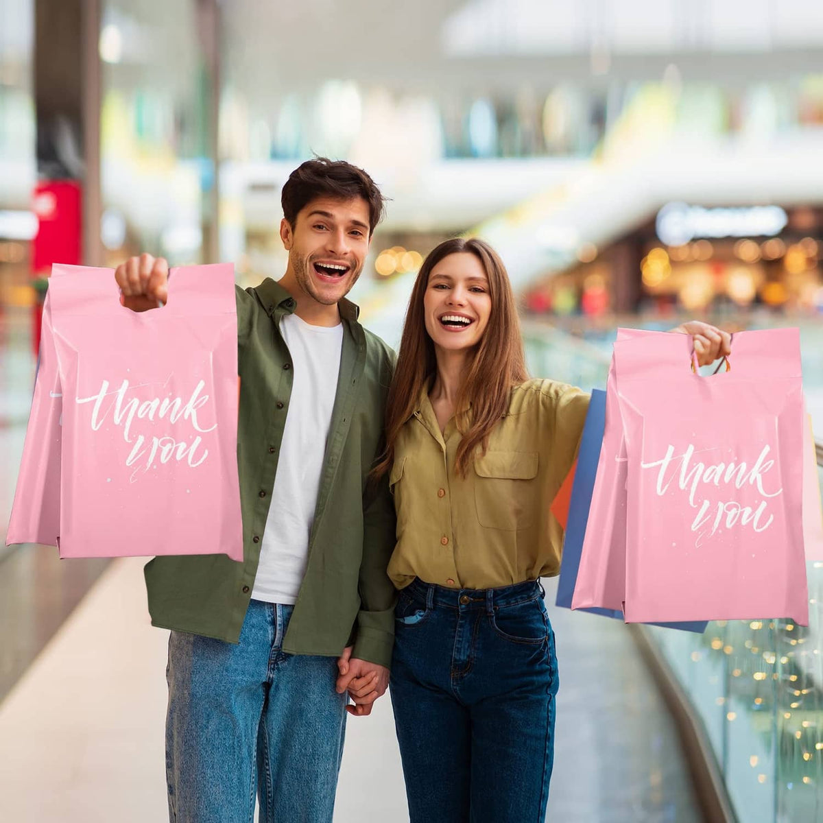 Pink “Thank you” poly mailer bags held by two people in a store aisle