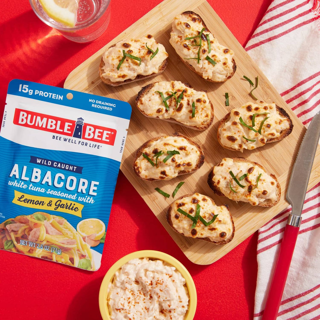 Albacore lemon and garlic tuna with crackers on a wooden serving board