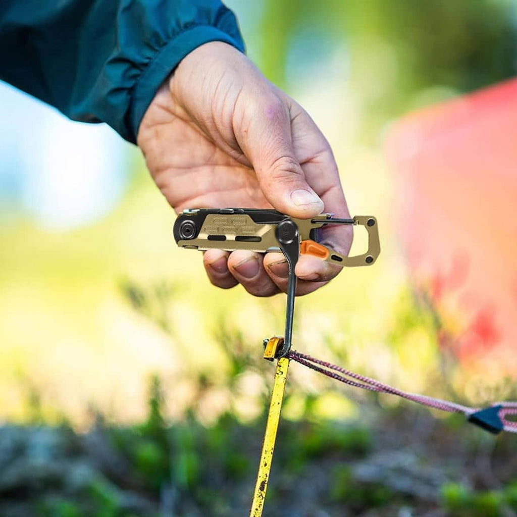 Hand holding tan-and-black multi-tool with orange tab while setting a camping cord
