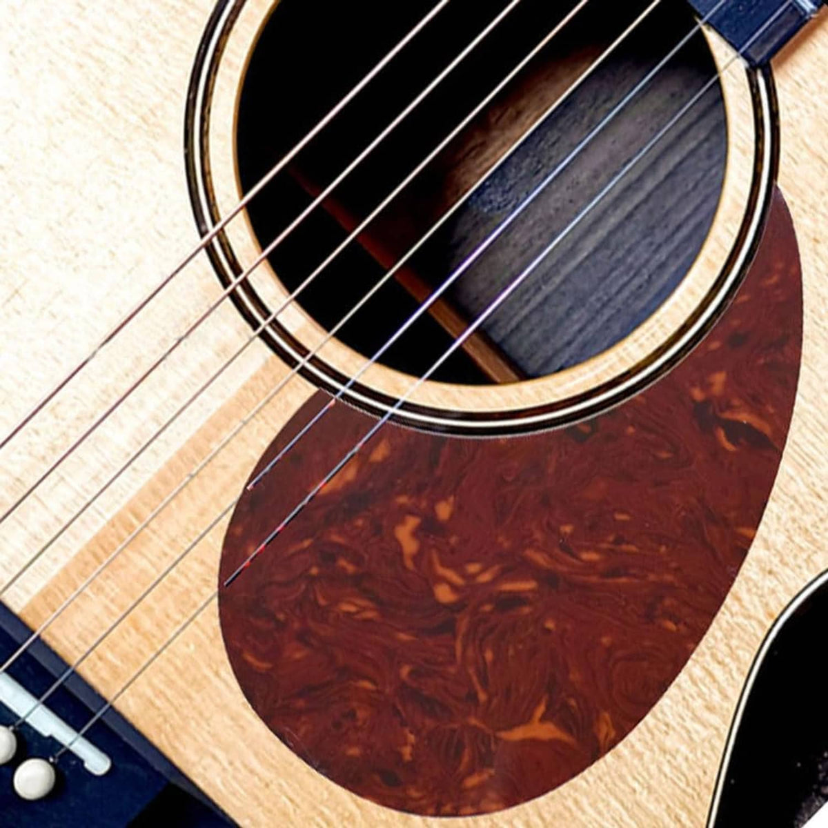 Travel guitar with dark red tortoiseshell pickguard around the soundhole