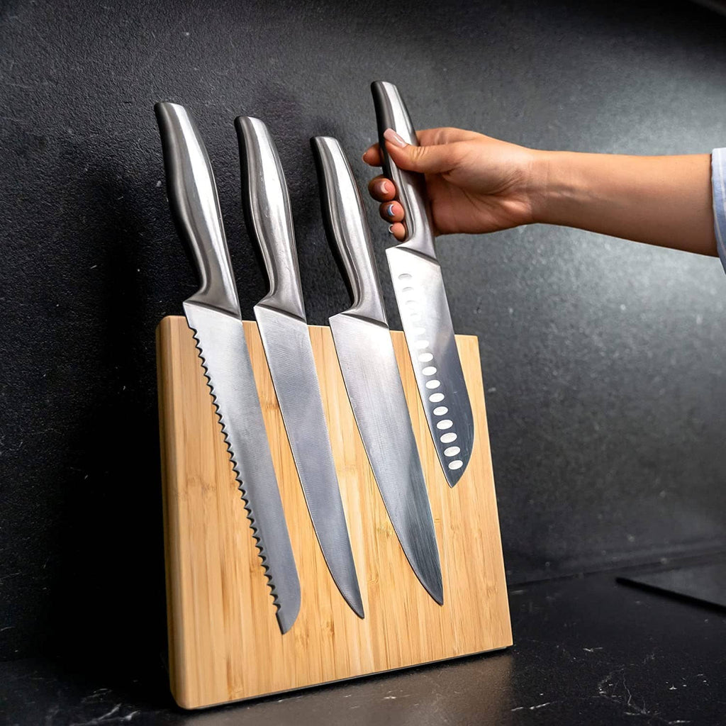 Coninx bamboo magnetic knife holder with knives; hand holding a chef knife