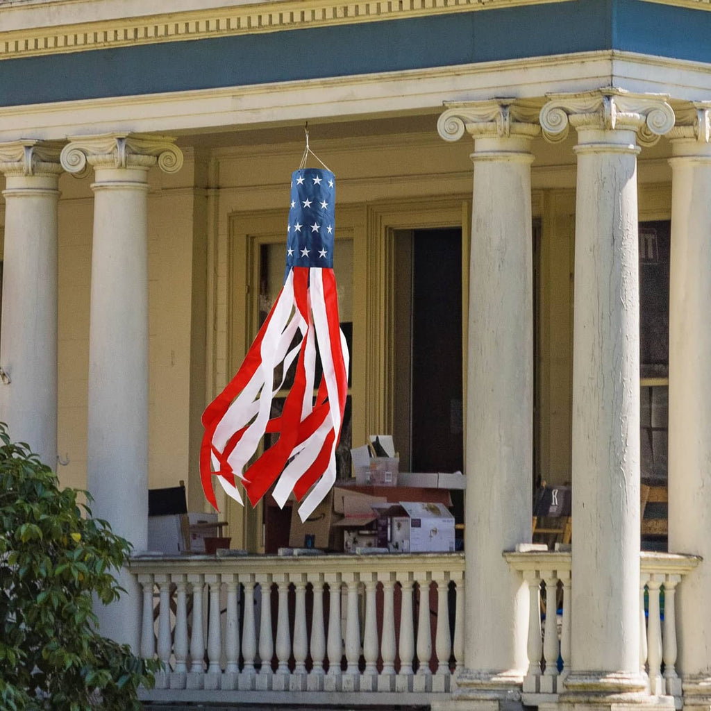 US flag windsock hanging on a front porch balcony with classical columns