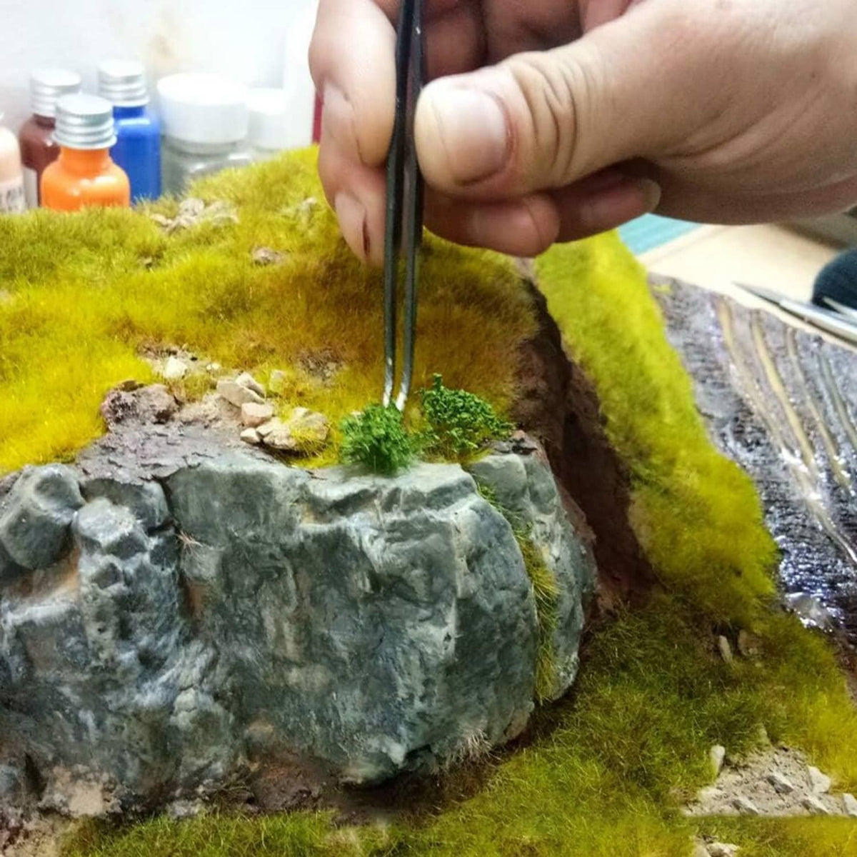 Green shrub tuft pieces applied to miniature terrain rock and grass