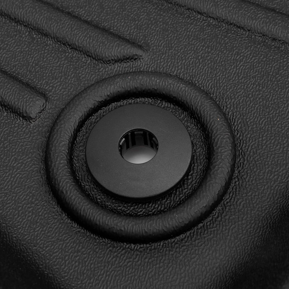 Round anchor grommet in black textured floor mat surface.