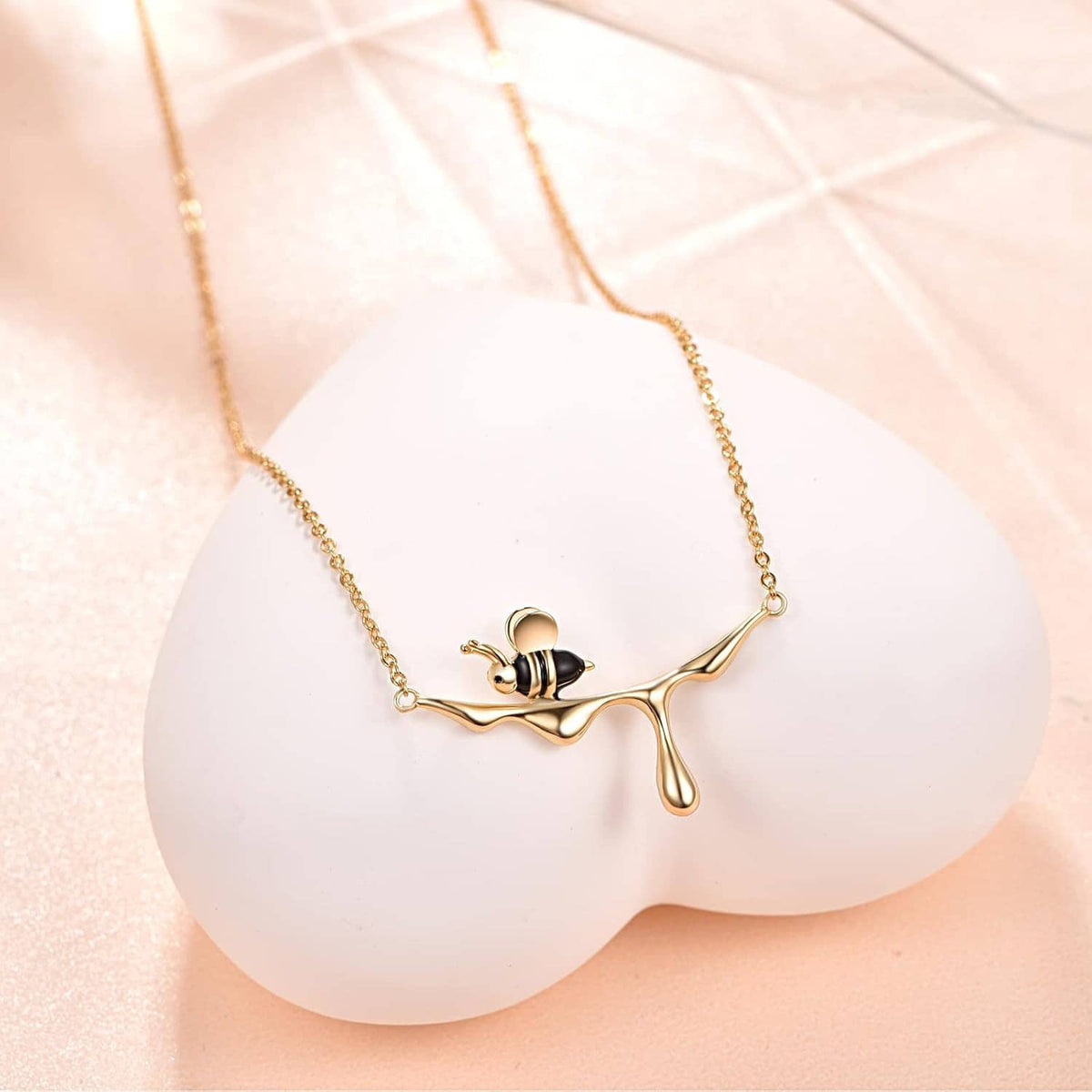 Gold-tone bee pendant necklace with black enamel body on a delicate chain