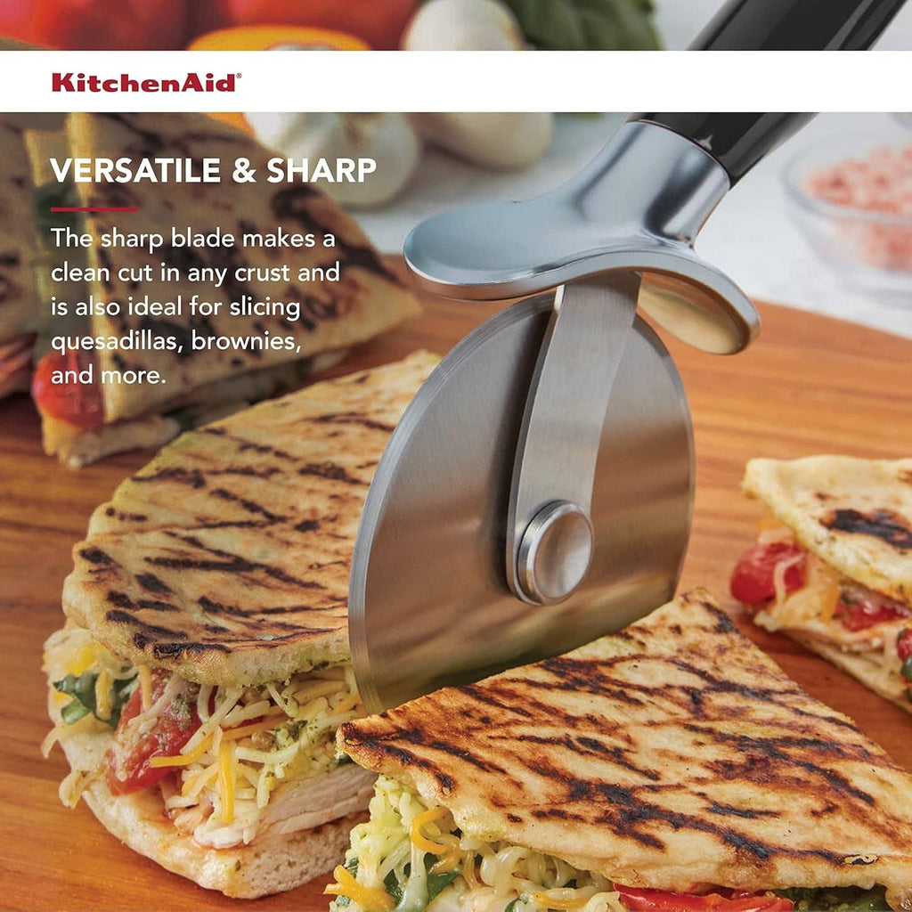Stainless pizza cutter wheel with black handle, cutting a flatbread pizza