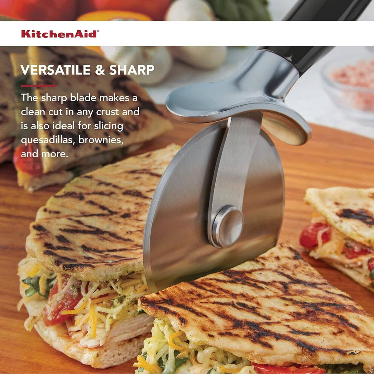 Stainless pizza cutter wheel with black handle, cutting a flatbread pizza