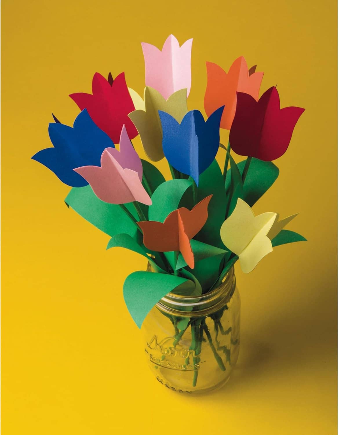 Assorted-color paper flower bouquet in a small glass jar