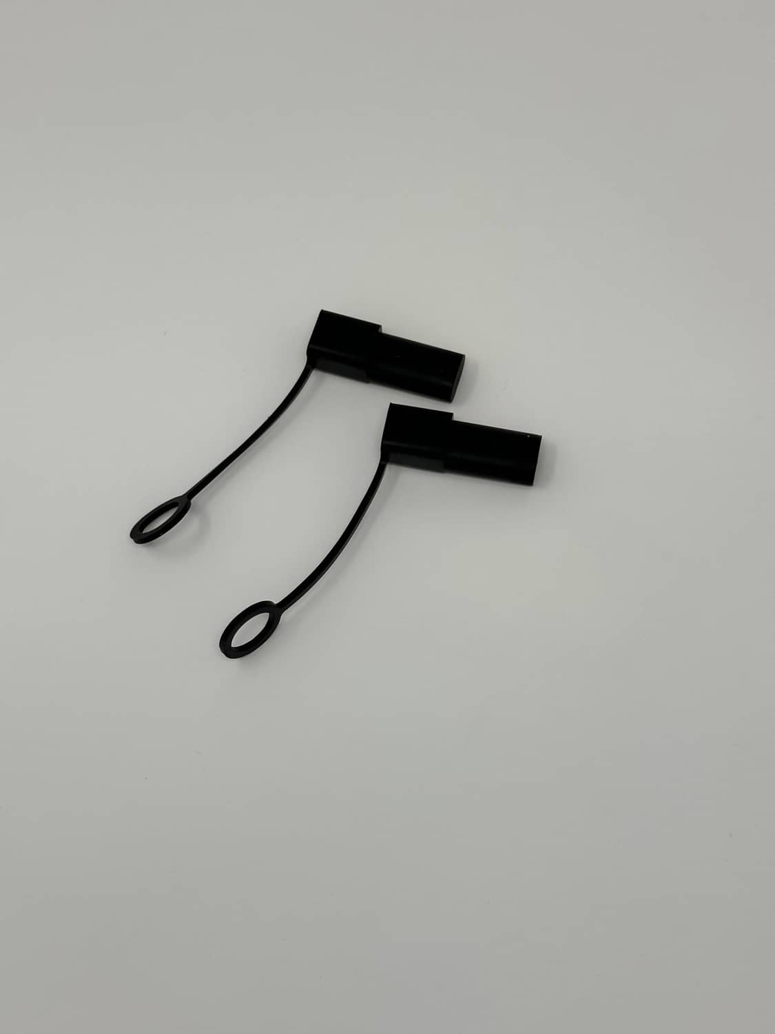 Pair of black silicone cable end caps with attached lanyard loops